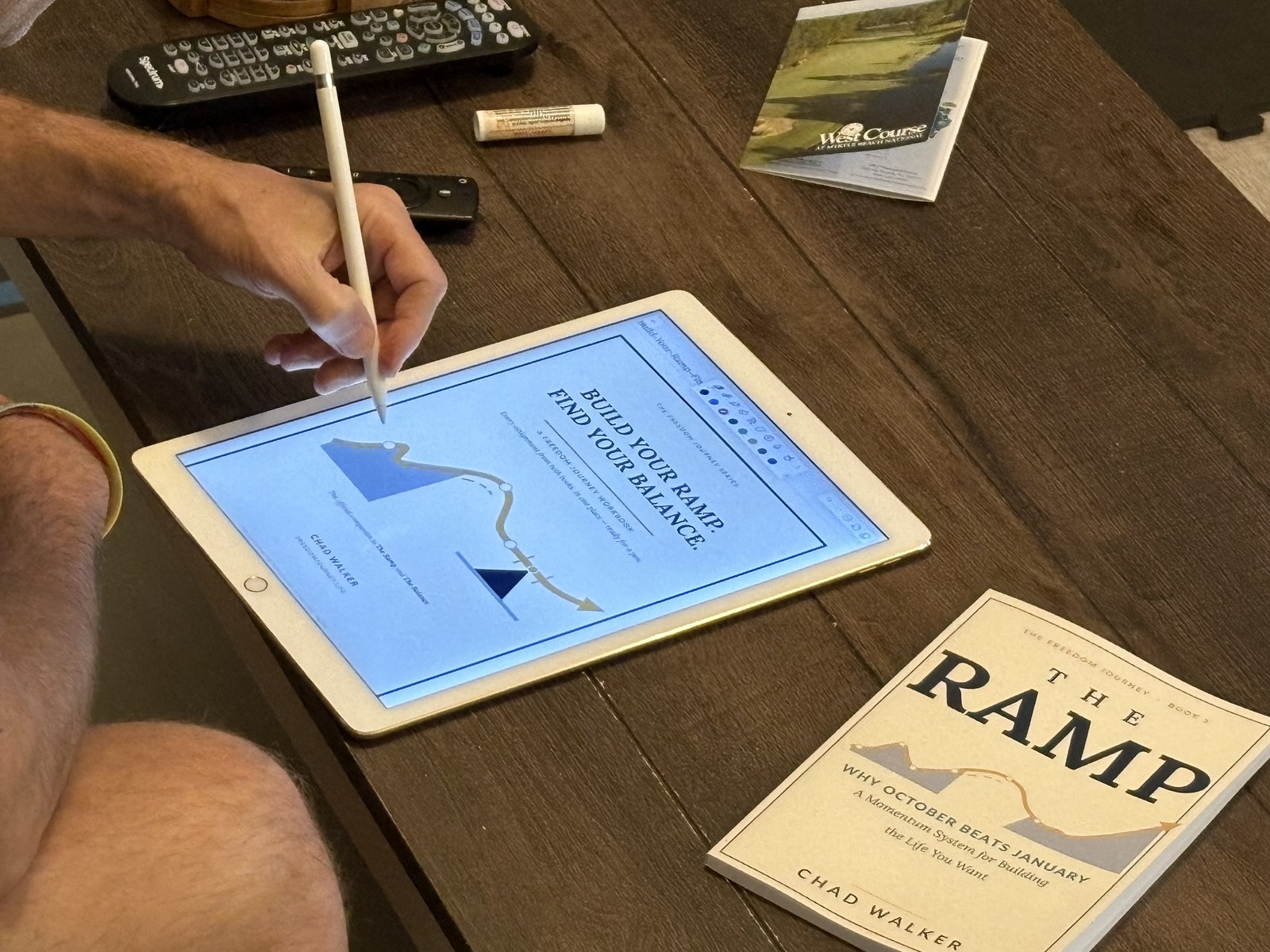 The Ramp workbook page open on an iPad beside a paperback copy of The Ramp by Chad Walker